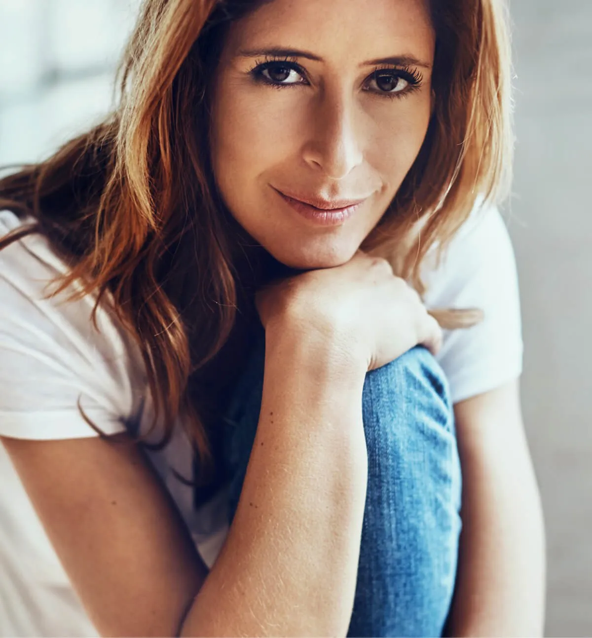 Woman leaning on her knee in jeans and a white t-shirt