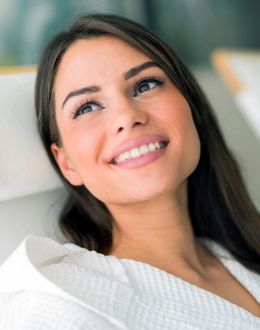 Smiling young woman with long dark hair, wearing a white robe, gazes upwards. Soft lighting enhances her bright eyes. - Morpheus 8 in West Chester Pike Newton Square, PA